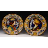 A PAIR OF VOLPI DERUTA MAJOLICA CHARGERS, each painted with a portrait and banner within a border of