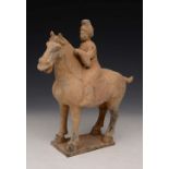 A CHINESE POTTERY TOMB FIGURE in the form of a woman riding a horse, 31cm high and 27cm long