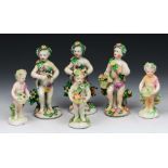 A COLLECTION OF SIX 19TH CENTURY ENGLISH PORCELAIN FIGURES of putti, each with a floral wreath and