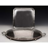 A SILVER PLATED OVAL TWO HANDLED BUTLERS TRAY with engraved decoration and bun feet, 63cm wide;