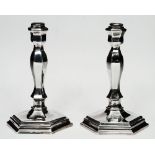 A PAIR OF SILVER HEXAGONAL SHAPED CANDLESTICKS with waisted shaped columns and stepped bases, 16cm