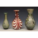 A GROUP OF THREE ROMAN GLASS VESSELS, two with green iridescence, 15cm and 11cm high, the other with