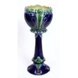 A LATE 19TH CENTURY POTTERY JARDINIERE AND STAND, blue glazed and with lily and leaf moulded