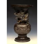 AN ORIENTAL BRONZE BALUSTER VASE with applied roaring dragon decoration on a circular base