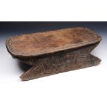 A PAPUA NEW GUINEA CARVED WOODEN STOOL with stylised double sided scrolling foliate and face