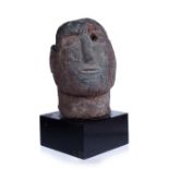 A PRIMITIVE RED STONE CARVED HEAD OF A MAN with Polynesian features on a square plinth, 23cm high