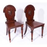 A PAIR OF EARLY VICTORIAN MAHOGANY HALL CHAIRS with panelled seats and carved armorial cartouche