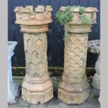 A near pair of castle top terracotta chimney pots, relief decorated with a trellis pattern,