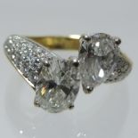 An 18 carat gold two stone crossover diamond ring, with cushion and pear shaped diamonds, approx 1.