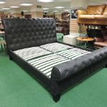 A black padded buttoned super king size double bedstead,