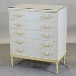 A cream painted chest of drawers, decorated with scrolls,