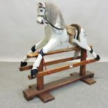 An early 20th century carved and painted wooden rocking horse, on a pine base,