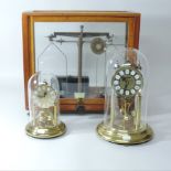 An anniversary clock, contained under a dome, together with another and a set of balance scales,