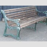 An Art Deco slatted wooden garden bench, with ornate green painted cast iron supports,