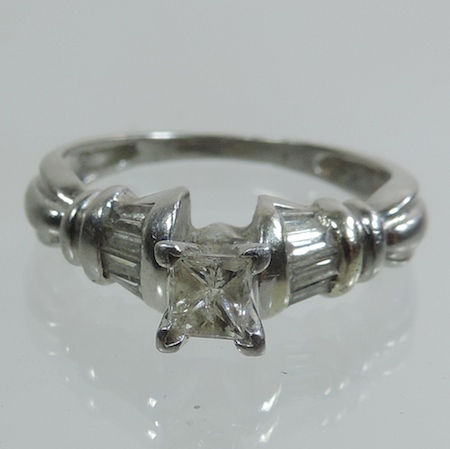 A 14 carat white gold princess cut diamond ring, with diamond set shoulders, approximately 0.