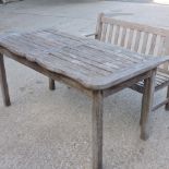 A teak slatted table, together with a similar bench,