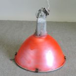 A red painted metal industrial light fitting,