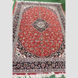 A Persian style rug, with a central medallion, on a red ground,