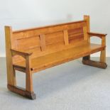 An early 20th century light oak pew, with a panelled back,