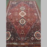 A Persian woollen carpet, with three central medallions, on a red ground,