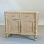 A pine sideboard, enclosed by panelled doors,