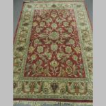 A Persian rug with all over floral designs, on a red ground,