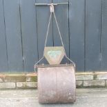 An iron garden roller, together with a green glazed planter,