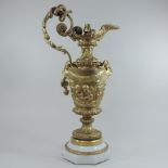 An ornate gilt bronze table lamp, in the form of a ewer, with relief decoration, on a marble base,