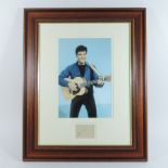 A photograph of Elvis Presley, mounted with his signature in blue ink on cream paper below, framed,