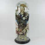 A Victorian taxidermy of a bird, amongst artificial flowers, contained under a glass dome,