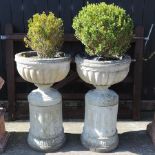 A pair of reconstituted stone urns, on pedestal bases,