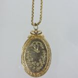 An early 20th century engraved oval locket and chain,