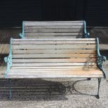 A near pair of slatted wooden garden benches, with green painted metal ends,