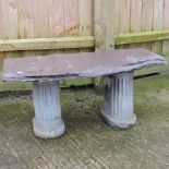 A slate garden bench, on column supports,