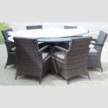 A circular rattan garden table, 135cm, together with a set of six chairs,