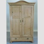 An antique pine armoire, with a drawer below,