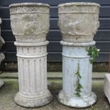 A pair of stone planters, each on a pedestal base,