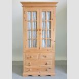 A modern glazed pine wardrobe, with drawers beneath,