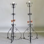 A pair of black painted iron candlesticks with plant pot holders,