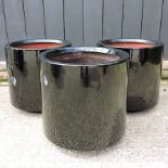 A set of three black circular garden planters,