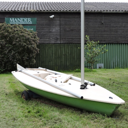 A Laser dinghy, with an aluminium mast, centreboard and rudder, on a trolley,