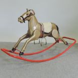 An early 20th century painted metal rocking horse, on a red painted rocker,