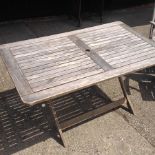 A teak slatted garden table, on a folding base,
