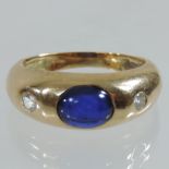 A yellow metal sapphire cabochon and diamond gypsy ring
