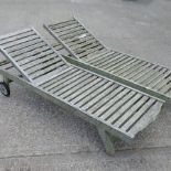 A pair of teak garden loungers