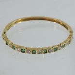 An 18 carat gold emerald and diamond hinged bangle
