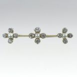 An unmarked split pearl and diamond set bar brooch, set as three flower heads, with a hinged clasp,