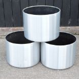 A set of three brushed aluminium garden pots,