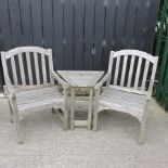 A pair of teak garden armchairs, together with a matching side table,