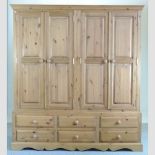 A modern pine four door wardrobe with drawers beneath,